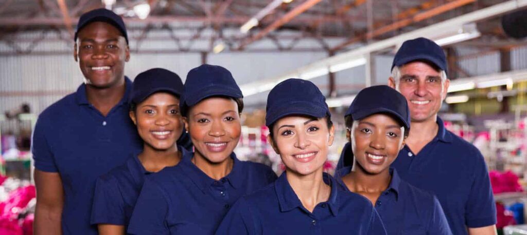 A group of happy clothing factory workers inside production area