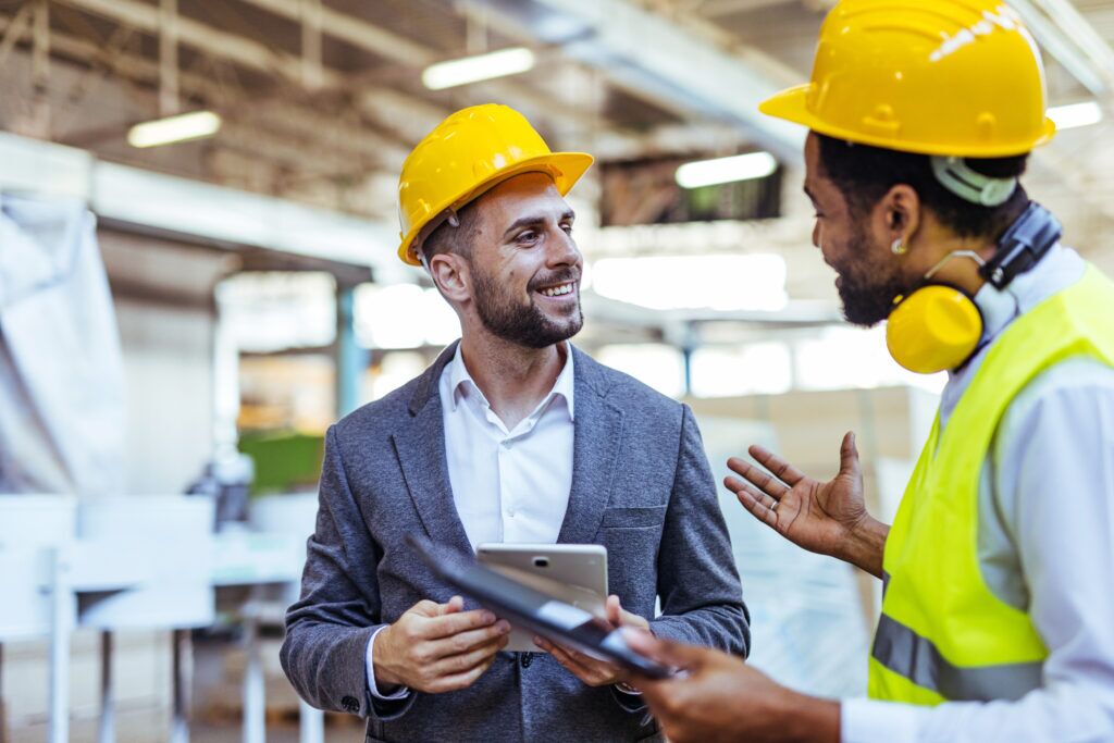 Two men wearing Hard-hats, discussing something
