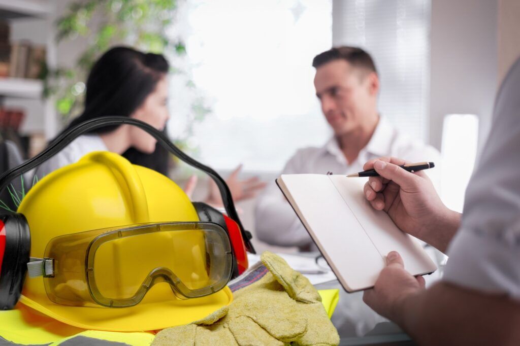 A yellow hard hat helmet alongside hearing protection and gloves