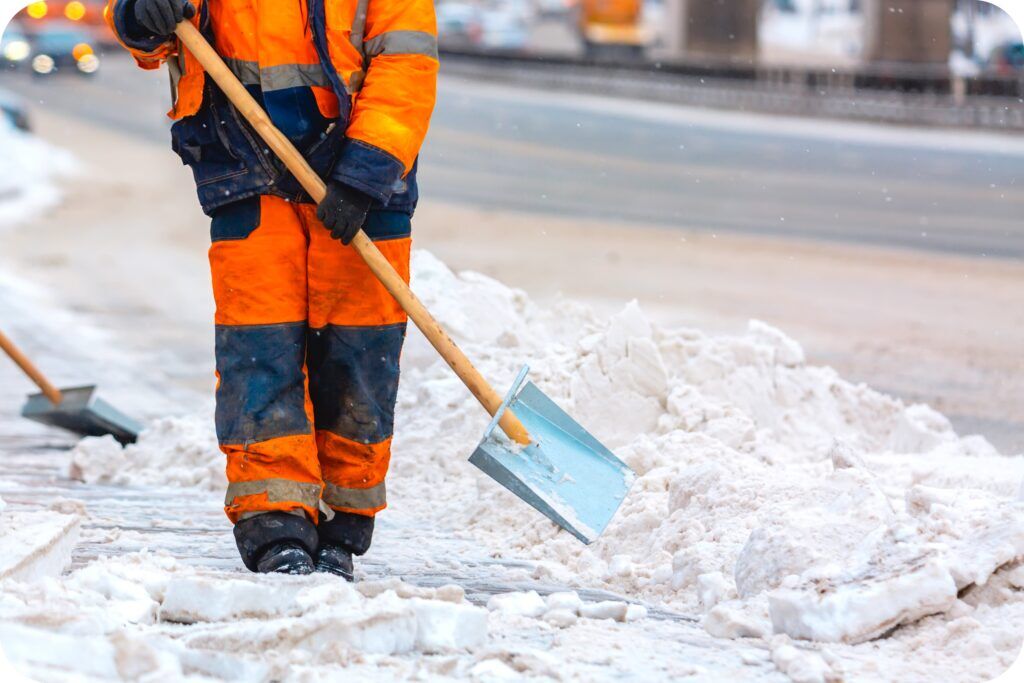 Maintenance staff applying ice melt on a slick pathway at night to improve traction and prevent injuries.