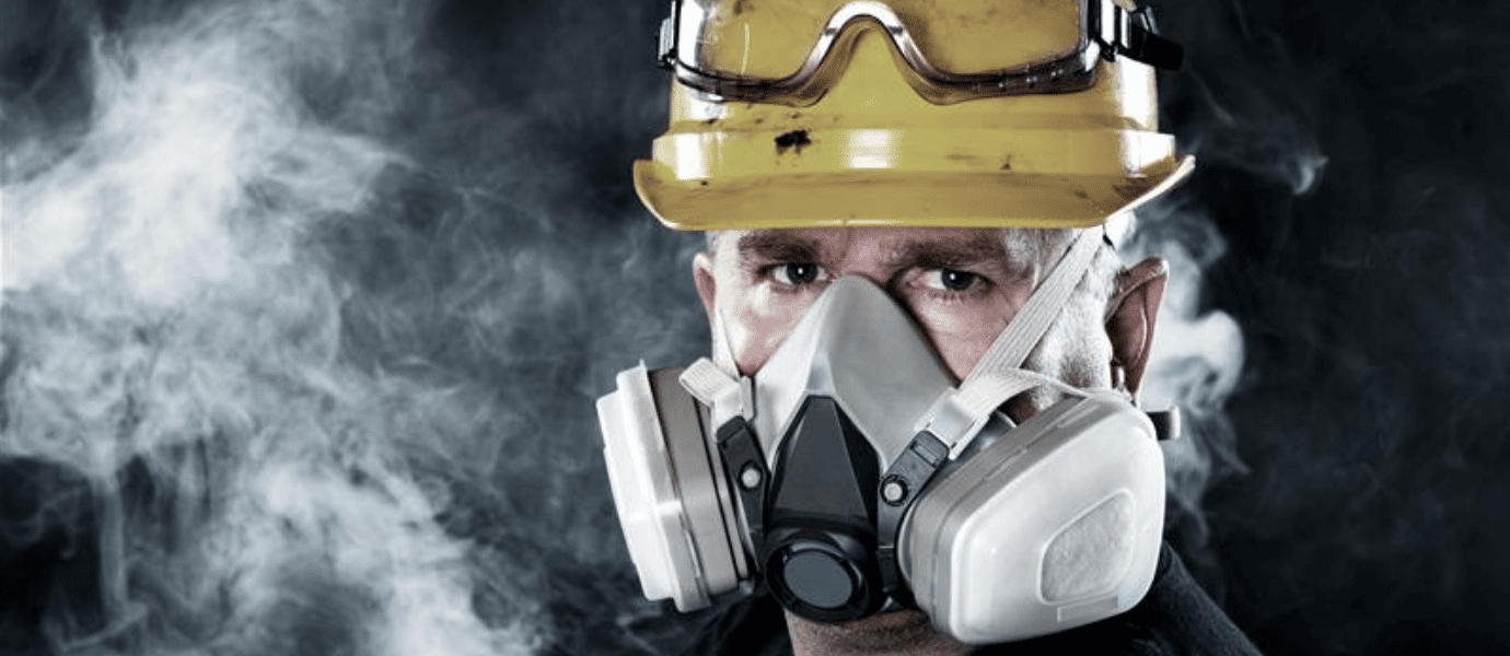 Worker wearing a safety mask and hard hat to protect against hazardous workplace gases.